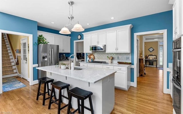4802 Worchester Pl, Jamestown, NC 27282 - kitchen featuring appliances with stainless steel finishes, a sink, a breakfast bar area, white cabinets, and decorative backsplash