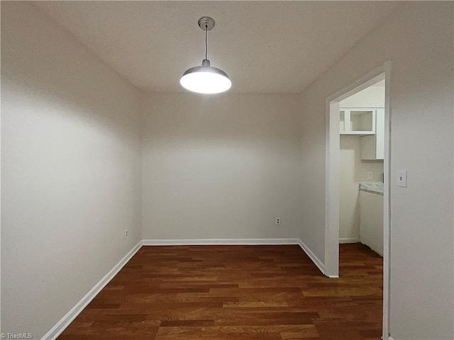 unfurnished dining area featuring wood finished floors and baseboards