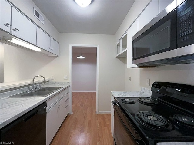 kitchen with stainless steel microwave, black range with electric stovetop, white cabinetry, a sink, and dishwashing machine