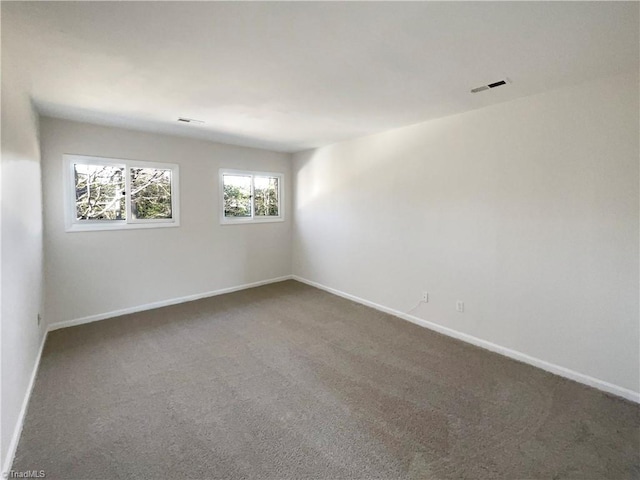 unfurnished room featuring carpet floors, visible vents, and baseboards