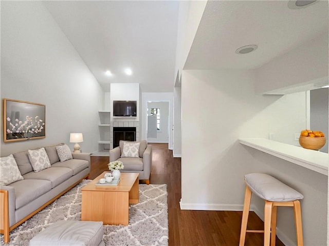 living room with lofted ceiling, wood finished floors, a tile fireplace, and baseboards