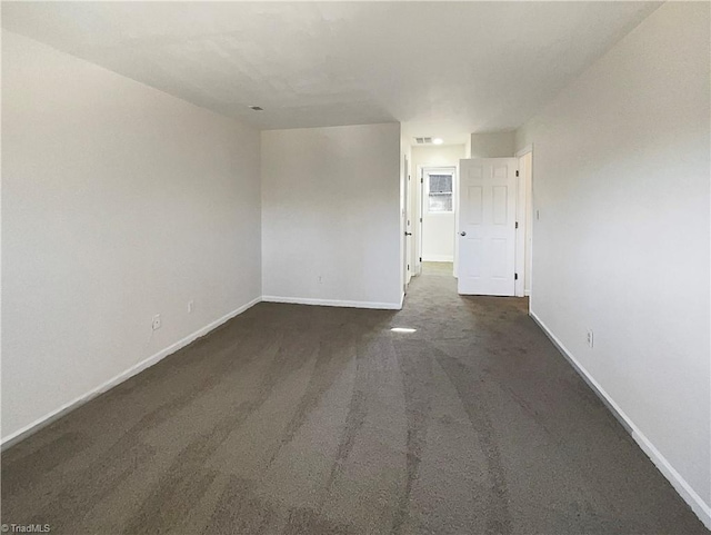 empty room with baseboards and dark colored carpet