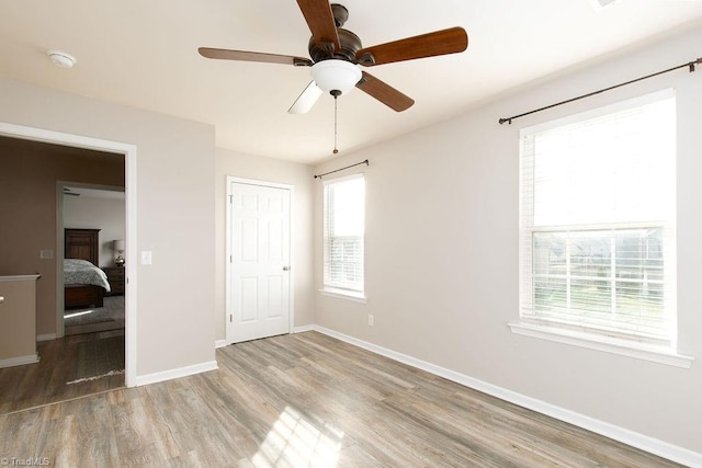 unfurnished bedroom with a closet, light hardwood / wood-style floors, multiple windows, and ceiling fan