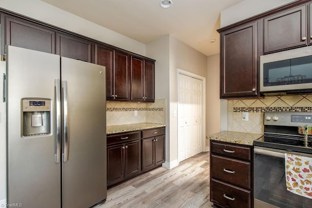 kitchen with appliances with stainless steel finishes, light wood-type flooring, tasteful backsplash, light stone counters, and dark brown cabinetry