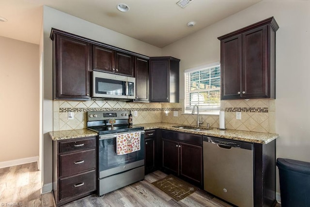 kitchen with decorative backsplash, stainless steel appliances, light hardwood / wood-style flooring, and sink