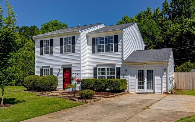 colonial house featuring french doors, a shingled roof, a front lawn, and fence