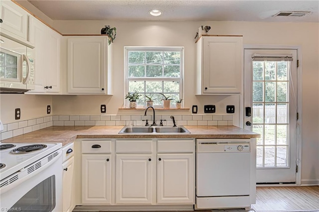 kitchen featuring a wealth of natural light, visible vents, white appliances, and a sink