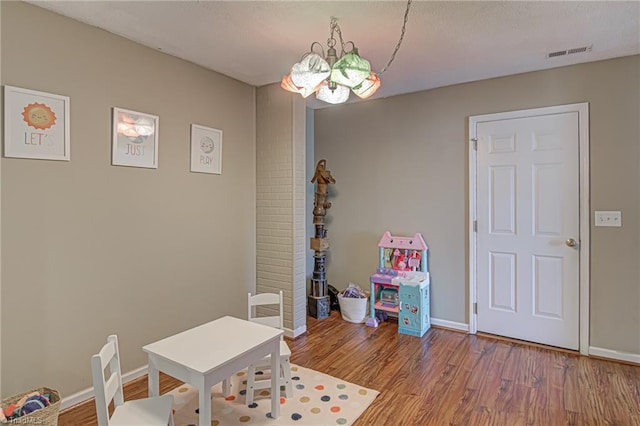 recreation room with visible vents, baseboards, wood finished floors, and a chandelier