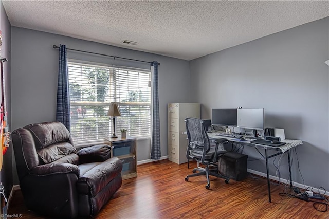 home office with visible vents, baseboards, a textured ceiling, and wood finished floors