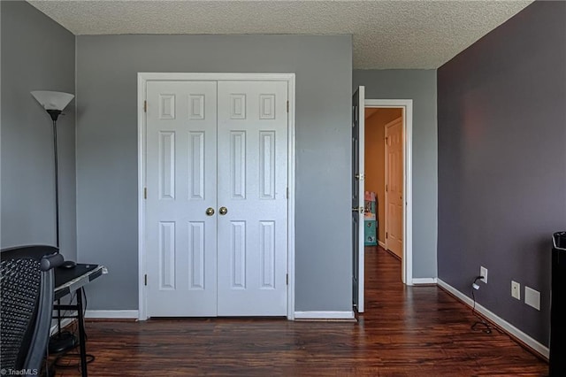 bedroom featuring a closet, a textured ceiling, baseboards, and dark wood-style flooring