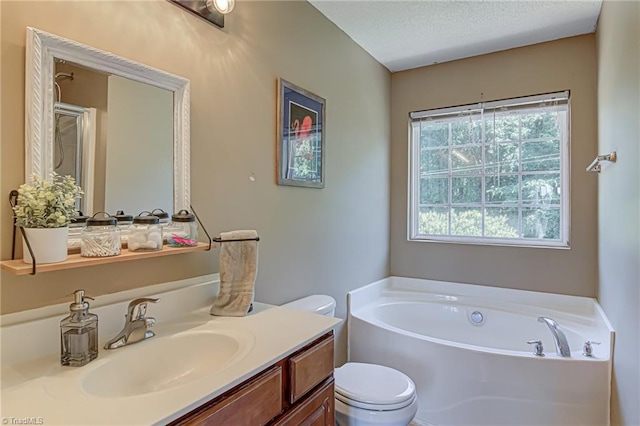 full bath with vanity, a garden tub, toilet, and a textured ceiling