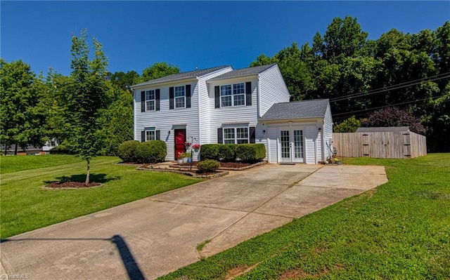 colonial-style house featuring french doors, concrete driveway, and a front lawn