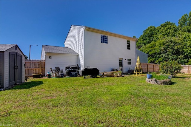 back of house with an outbuilding, a storage shed, a lawn, and fence