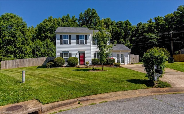 colonial house featuring a front lawn and fence