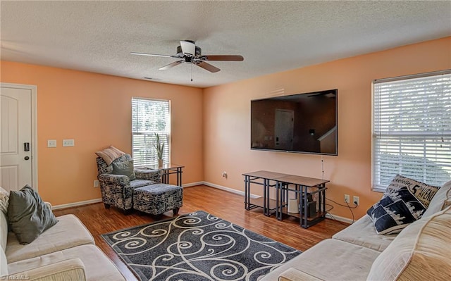 living room featuring visible vents, baseboards, wood finished floors, and a ceiling fan