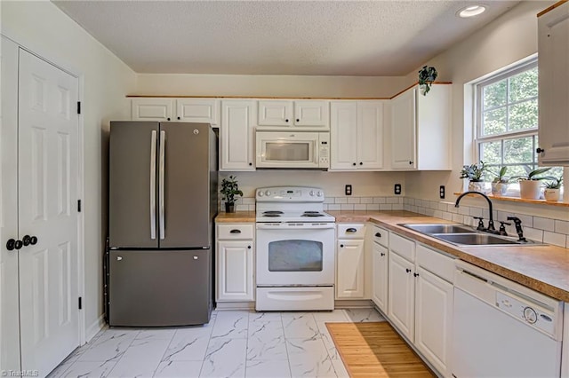 kitchen with marble finish floor, a sink, white cabinetry, white appliances, and light countertops