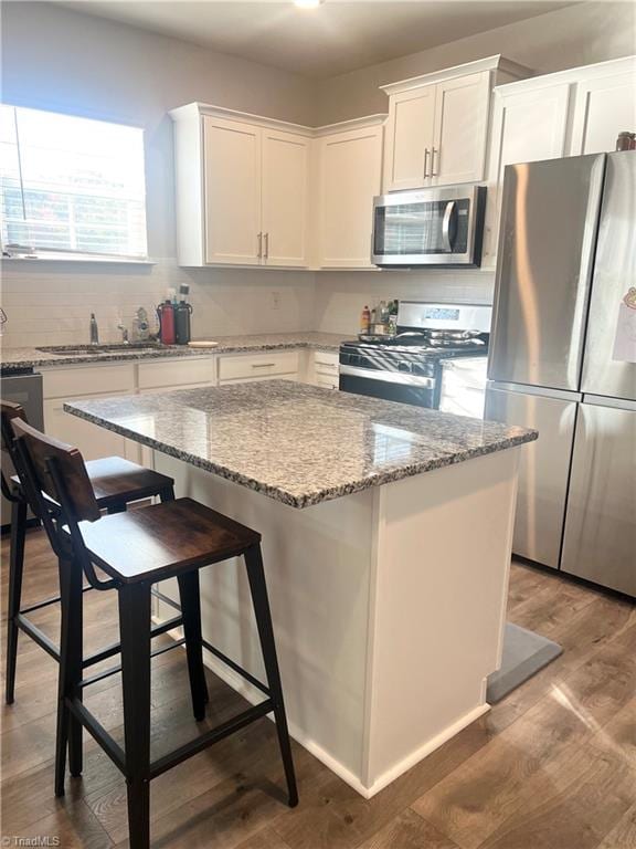 kitchen featuring white cabinets, hardwood / wood-style floors, stainless steel appliances, and a kitchen island