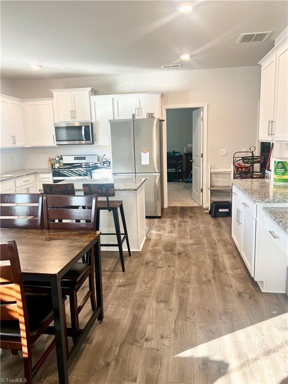 kitchen with light stone counters, white cabinetry, and appliances with stainless steel finishes