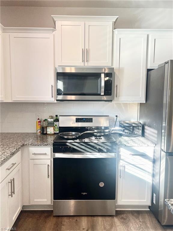 kitchen with light stone countertops, white cabinetry, stainless steel appliances, and dark hardwood / wood-style floors