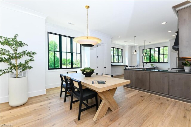 dining room with light wood finished floors, crown molding, baseboards, and recessed lighting