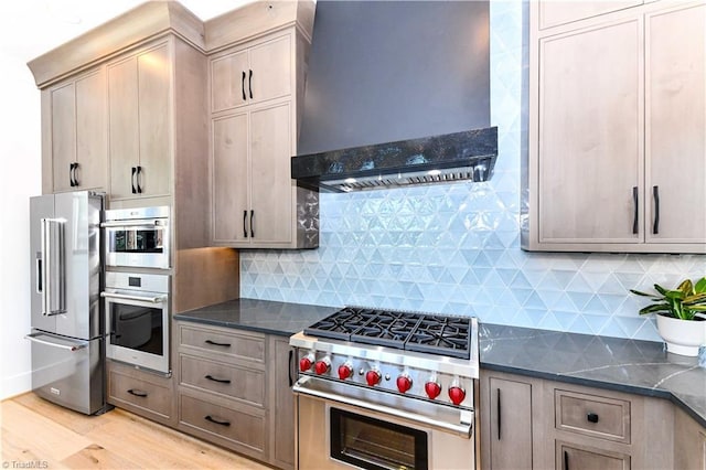 kitchen with high quality appliances, tasteful backsplash, light wood-style flooring, and custom exhaust hood