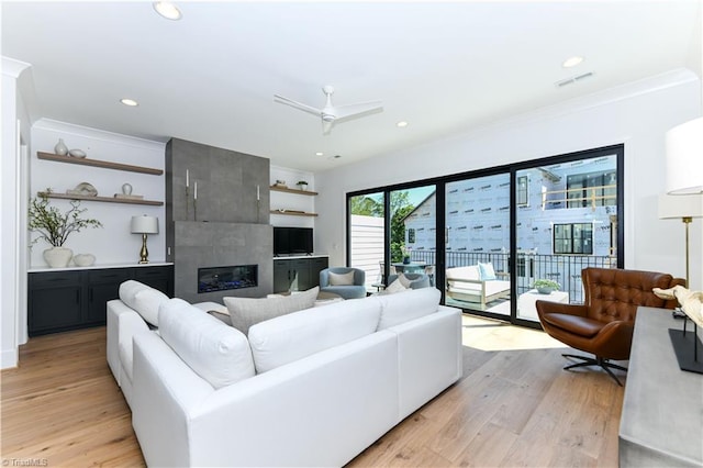 living area with light wood-type flooring, visible vents, recessed lighting, a ceiling fan, and a tile fireplace