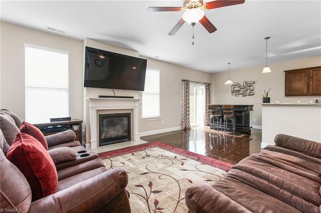 living room featuring wood finished floors, visible vents, a fireplace, ceiling fan, and baseboards
