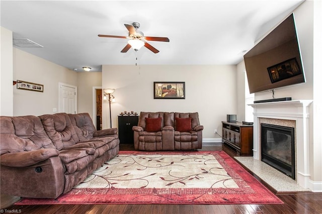 living room with a ceiling fan, baseboards, a glass covered fireplace, visible vents, and wood finished floors