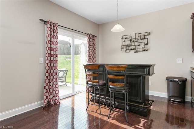 bar with baseboards, a wealth of natural light, dark wood finished floors, and a bar