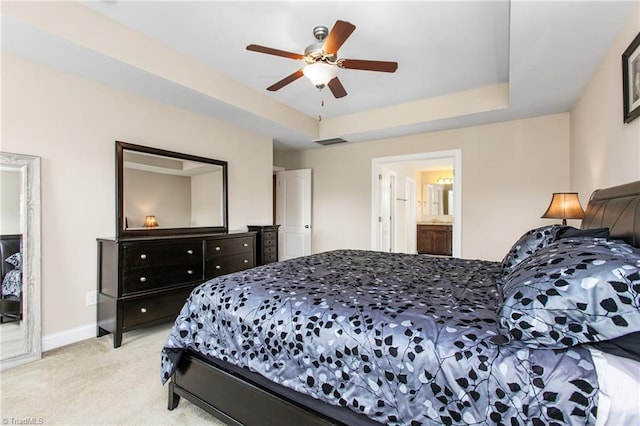 bedroom featuring a ceiling fan, a tray ceiling, baseboards, visible vents, and light carpet