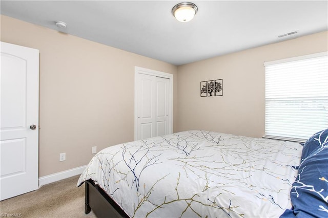 carpeted bedroom featuring a closet, visible vents, and baseboards