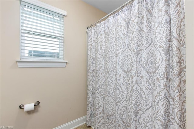 bathroom with plenty of natural light, baseboards, and a shower with curtain