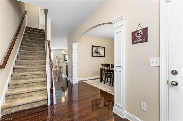 entryway featuring decorative columns, stairway, arched walkways, dark wood-style floors, and baseboards