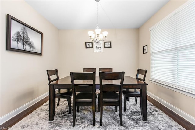 dining space with an inviting chandelier, dark wood-style flooring, and baseboards