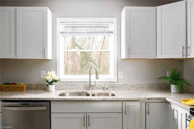 kitchen featuring light stone counters, white cabinets, sink, and dishwasher