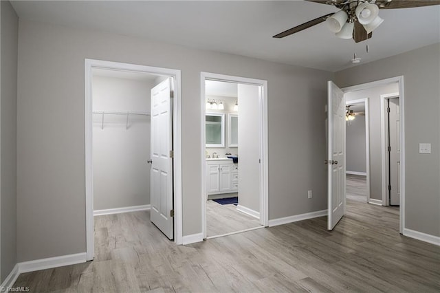 unfurnished bedroom with a closet, a walk in closet, ensuite bath, and light hardwood / wood-style flooring