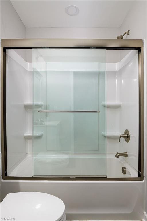 bathroom with toilet and shower / bath combination with glass door