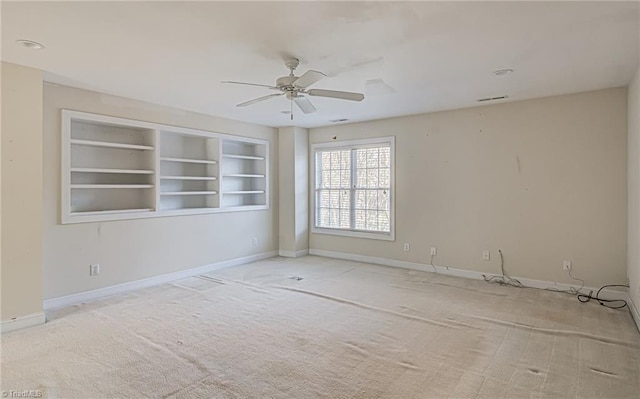 spare room with ceiling fan, built in features, and carpet floors