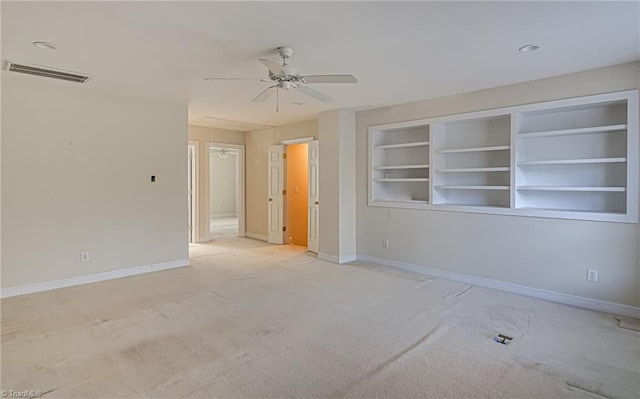 carpeted empty room featuring built in shelves and ceiling fan