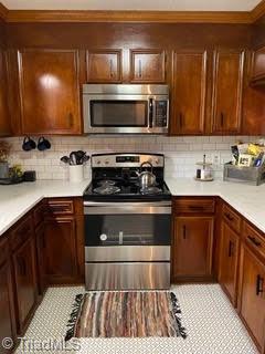 102 Aspen Ct, Winston-Salem, NC 27106 - kitchen featuring stainless steel appliances, light countertops, backsplash, ornamental molding, and light tile patterned floors