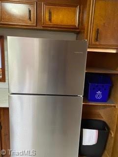 102 Aspen Ct, Winston-Salem, NC 27106 - detailed view of freestanding refrigerator, brown cabinets, and light countertops