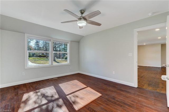 empty room with dark hardwood / wood-style floors, vaulted ceiling, and ceiling fan