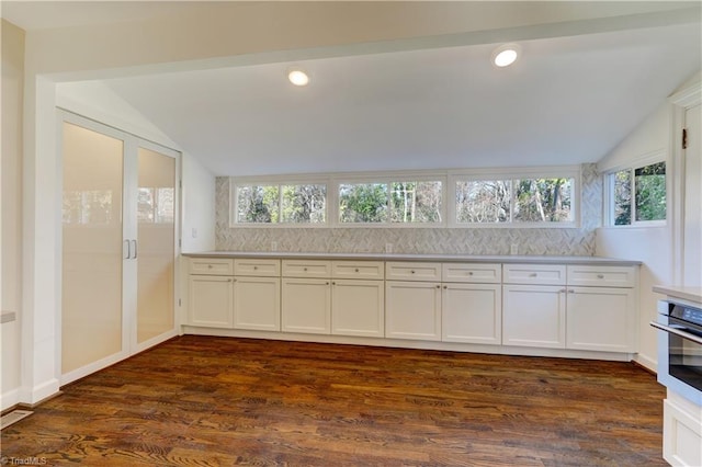 kitchen featuring white cabinets, dark hardwood / wood-style flooring, oven, and vaulted ceiling