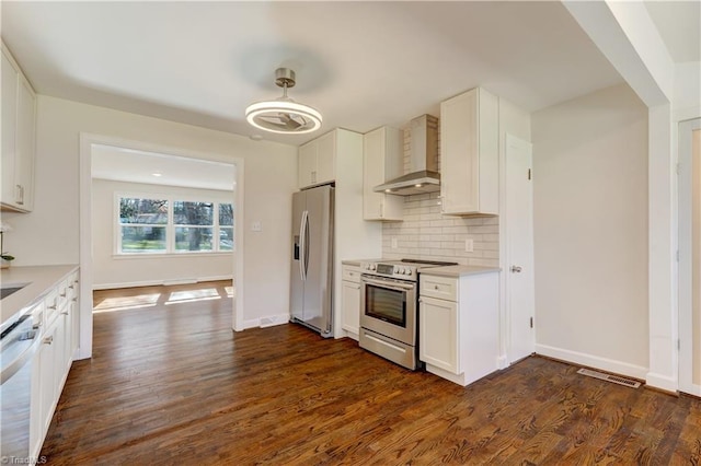 kitchen featuring appliances with stainless steel finishes, tasteful backsplash, dark wood-type flooring, wall chimney range hood, and white cabinetry