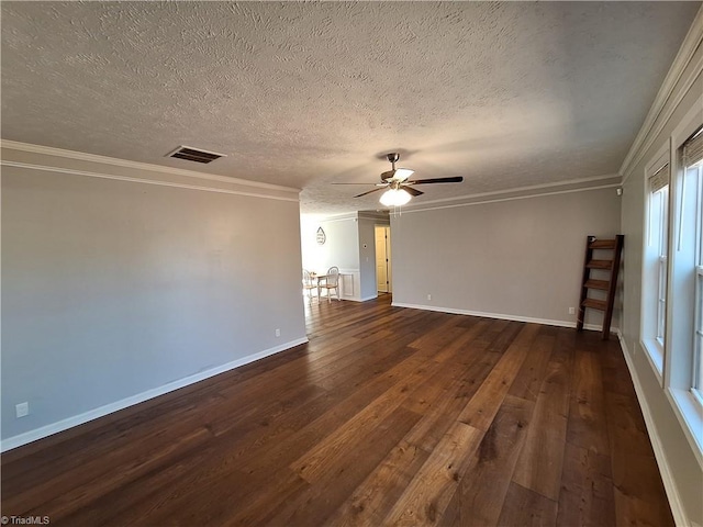 spare room with visible vents, baseboards, a ceiling fan, ornamental molding, and dark wood finished floors