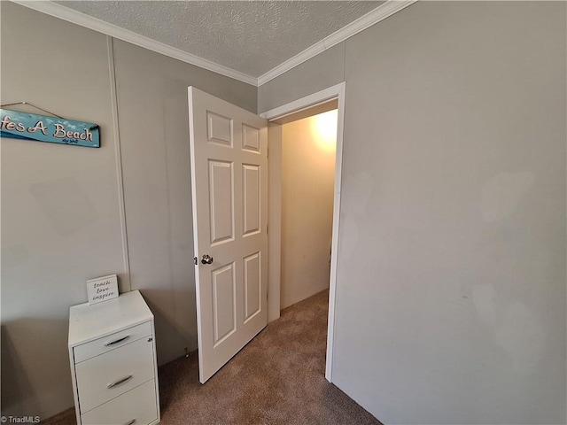 hallway featuring a textured ceiling, ornamental molding, and carpet flooring