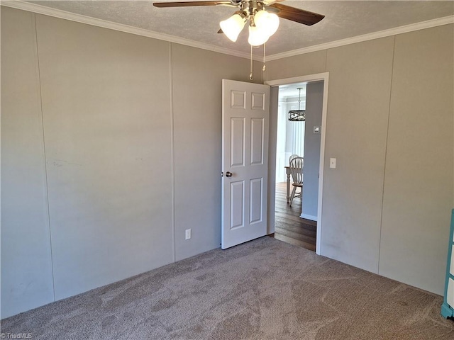 empty room featuring ceiling fan, ornamental molding, a textured ceiling, carpet flooring, and a decorative wall