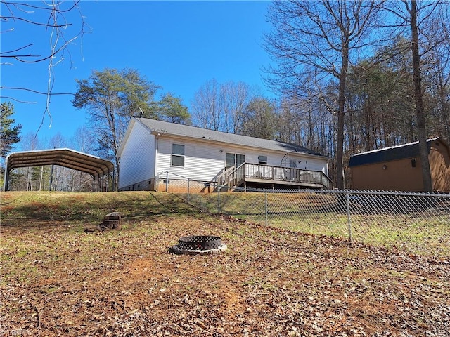 back of house featuring a fire pit, crawl space, fence, a wooden deck, and a carport