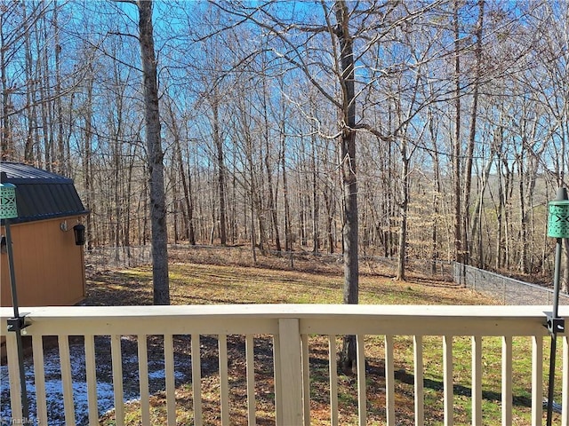 view of yard with an outbuilding, a forest view, and fence