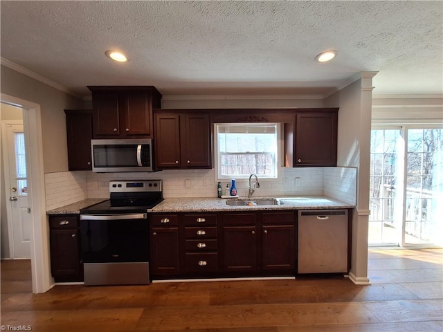 kitchen featuring stainless steel appliances, dark brown cabinets, dark wood-style flooring, and a sink